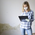 pretty young woman standing front wall with mold with tablet mouth nose mask person (fileminimizer)